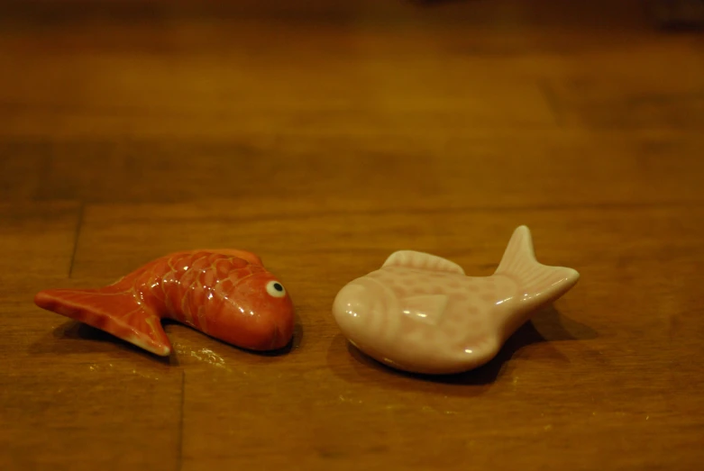 two tiny fish figurines placed on a wooden floor