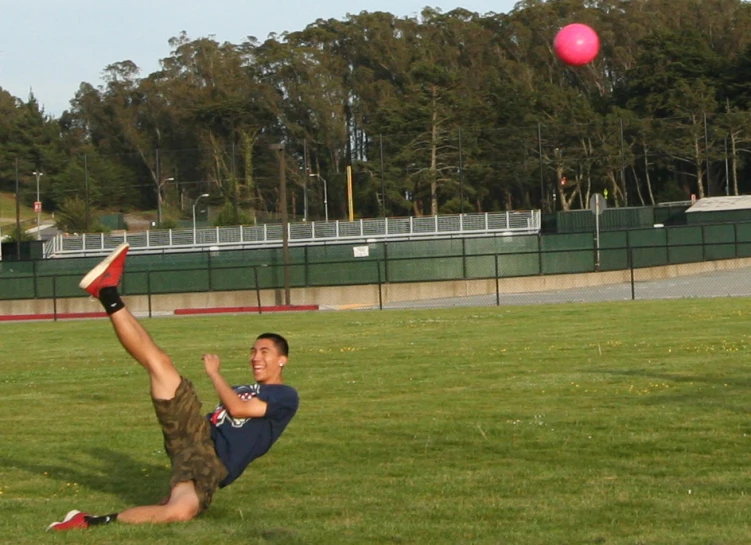 the young man lays down in the grass as the red disc comes to land