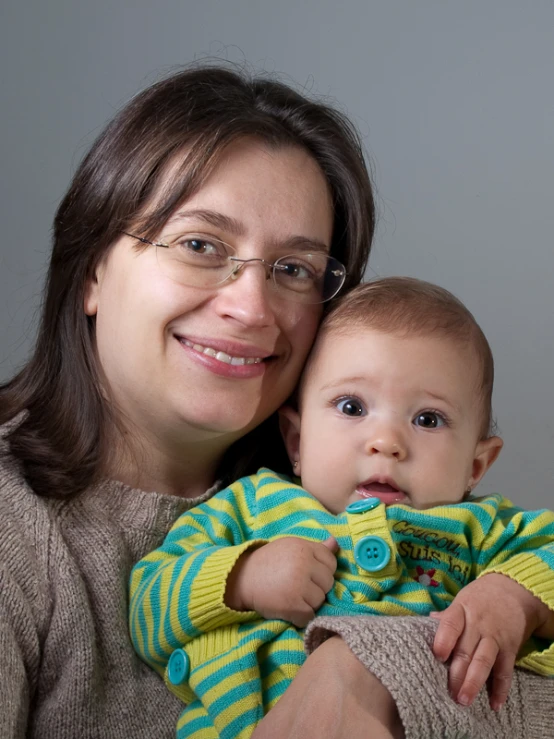 a woman holds a baby wearing glasses