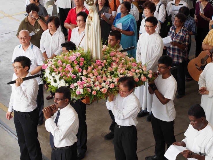 a group of people holding flowers and singing together