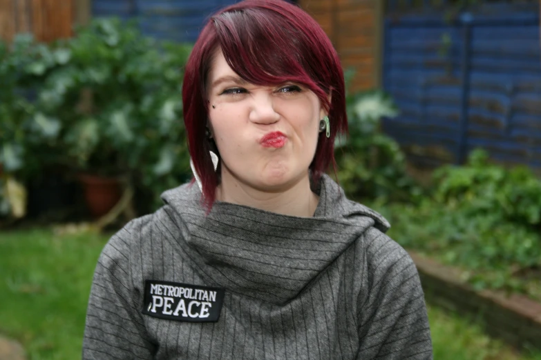 a woman with red hair and piercings making a funny face