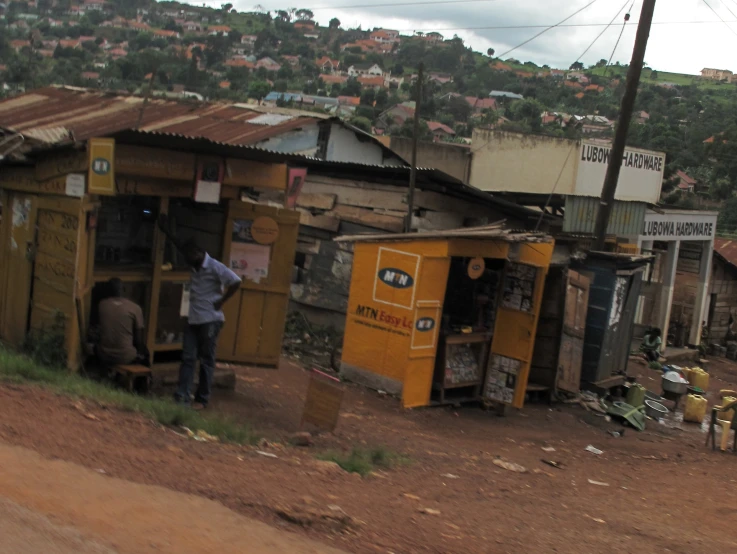 a shack and some people standing outside near the street