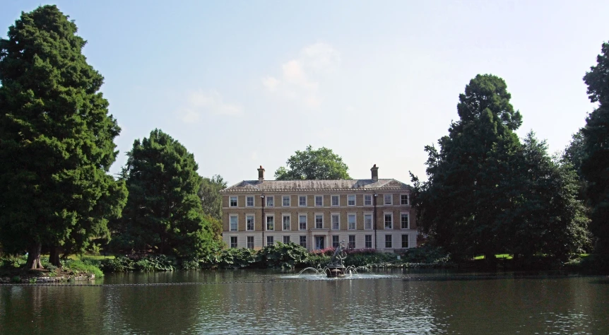 an old mansion by a lake with some people swimming