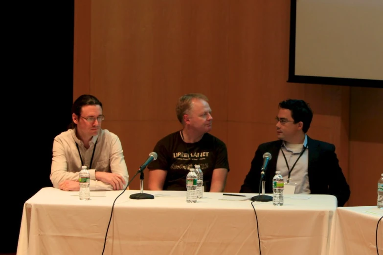 three men sitting around a table with microphones