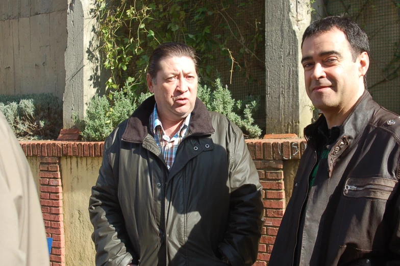 three men in front of a building talking