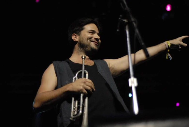 a male musician holding a trombone in front of a microphone