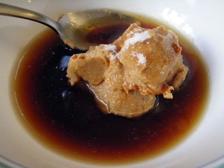 brown powder sits in the bowl of sauce and spoon