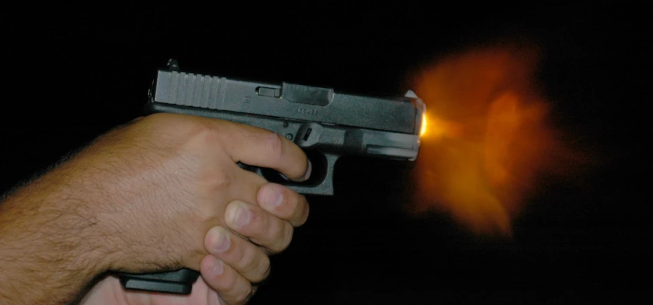 a person holding a gun as it is lit in the dark