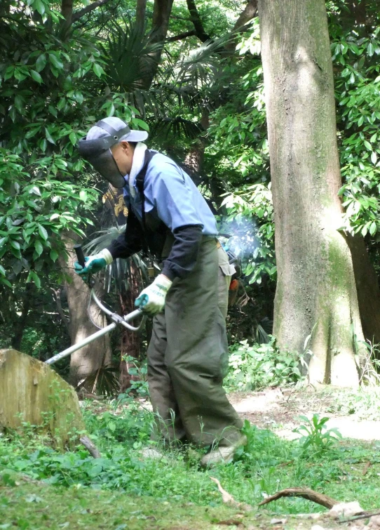 man in green field working with tools near trees