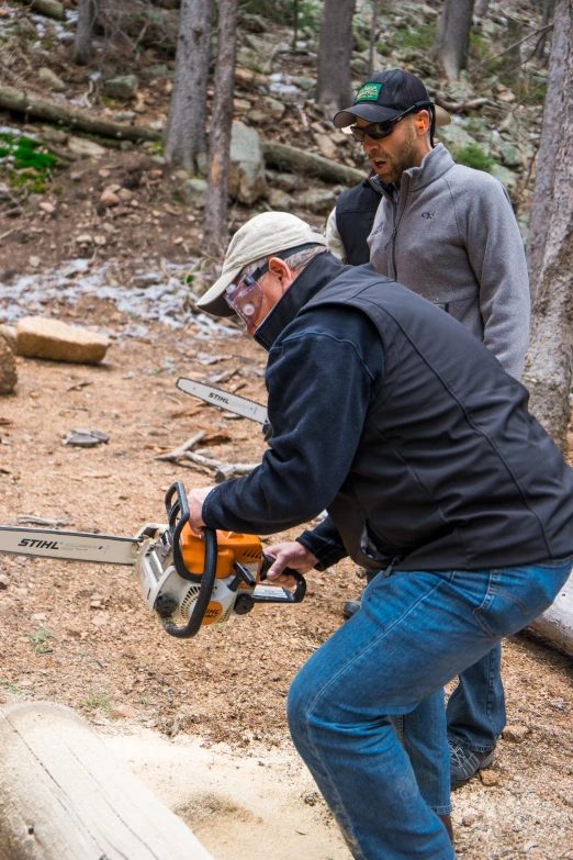 two men are using chainsaws to cut a log