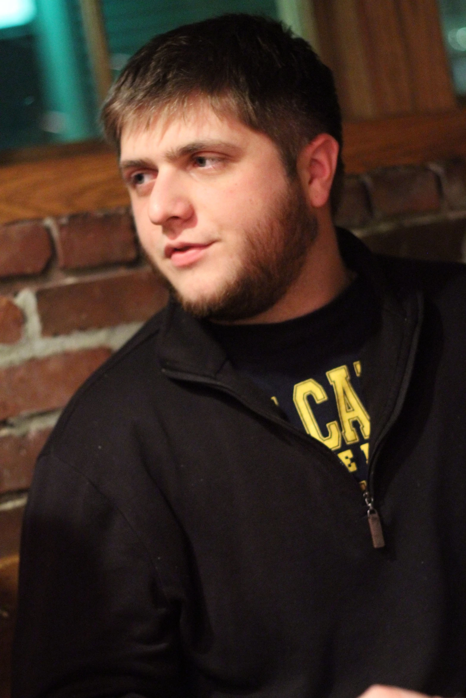 a man standing in front of a brick wall with a tie around his neck