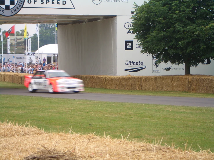 a race car drives past a grassy track and a barn