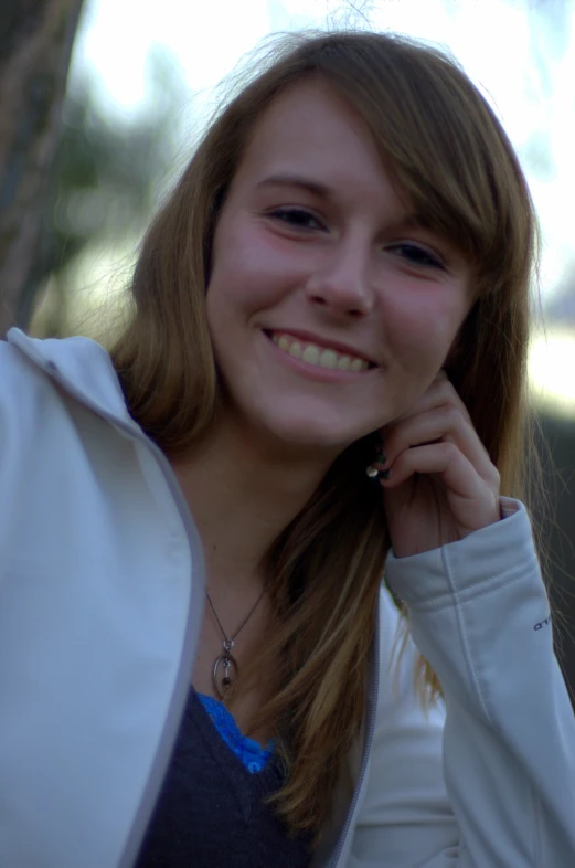 a girl smiling at the camera while wearing a white jacket