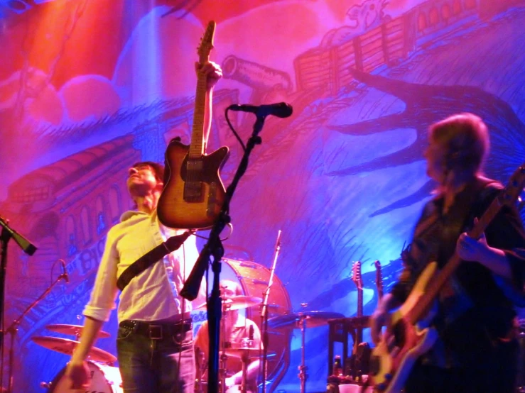 two men are standing at a stage while playing guitars