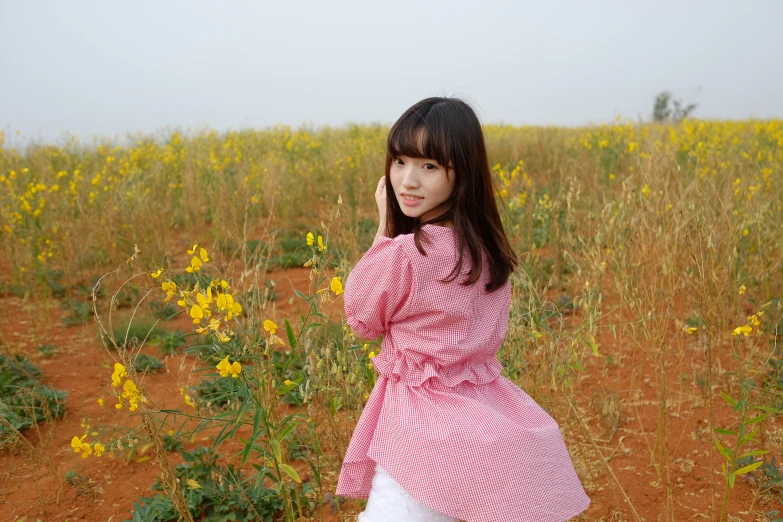 a woman in a field that is surrounded by yellow flowers