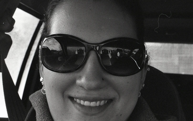black and white po of woman in sunglasses in car