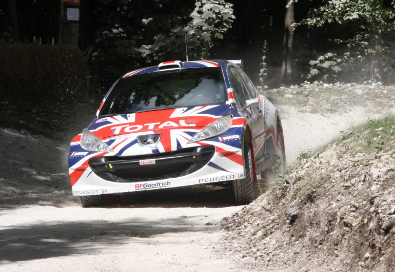 an automobile with british flag paint driving on the dirt road