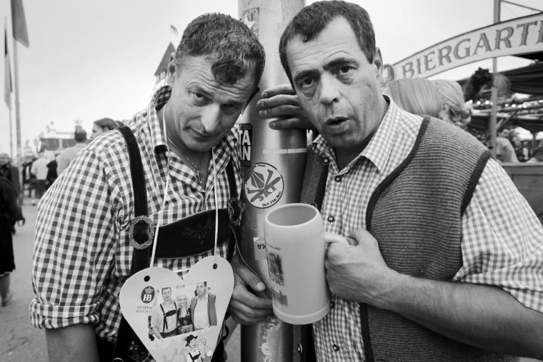 two men pose next to each other with coffee cups in hand