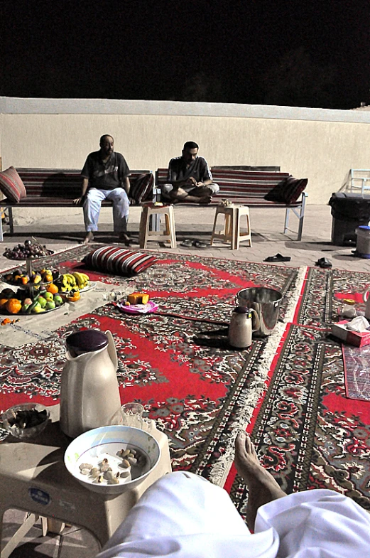 a group of people sitting on a carpet with food