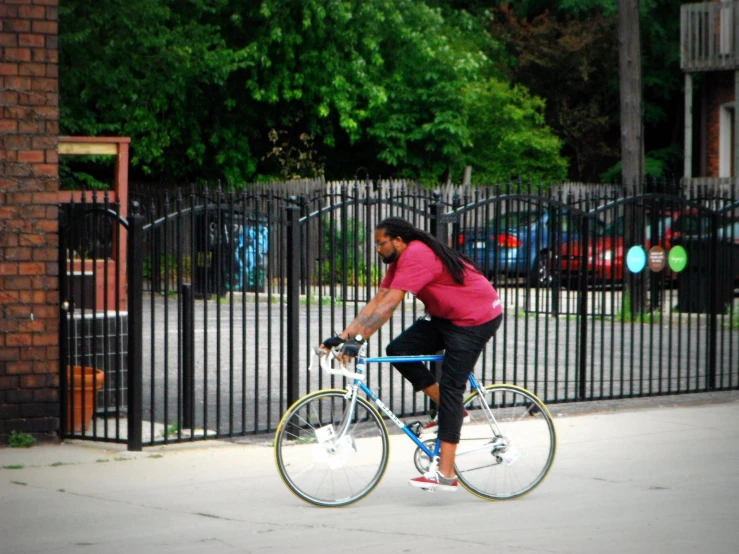 a girl rides her bike in front of a fence