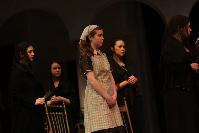 a women in a costume looking on as other women in dresses watch