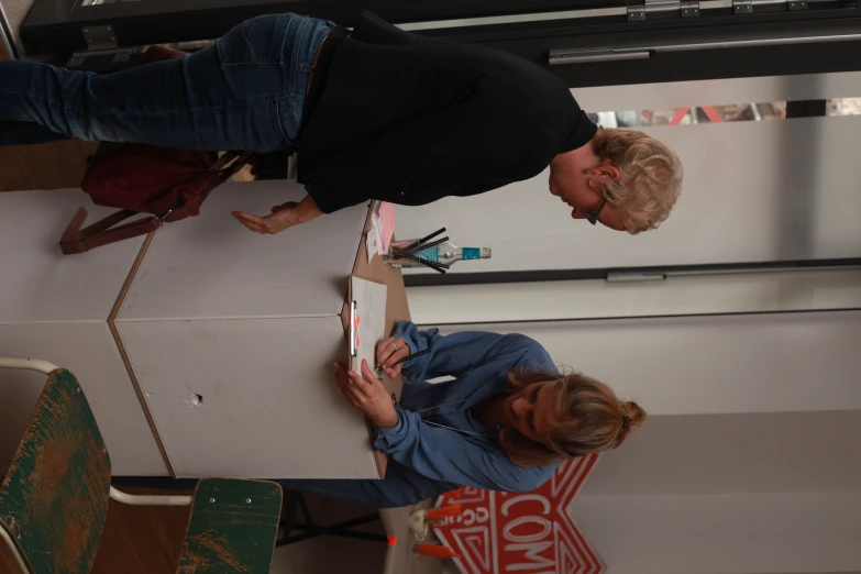 a woman looking over a closed box while someone sign soing