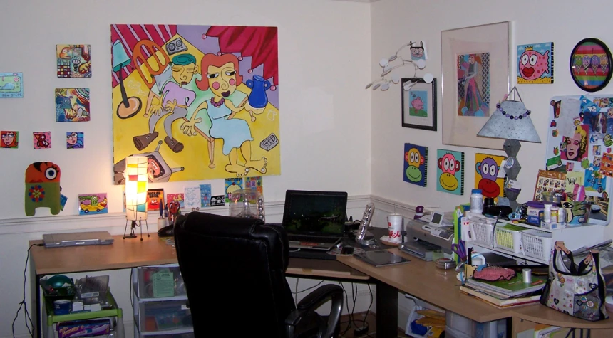 a large collection of comics and other art sits on the wall above a desk with a computer