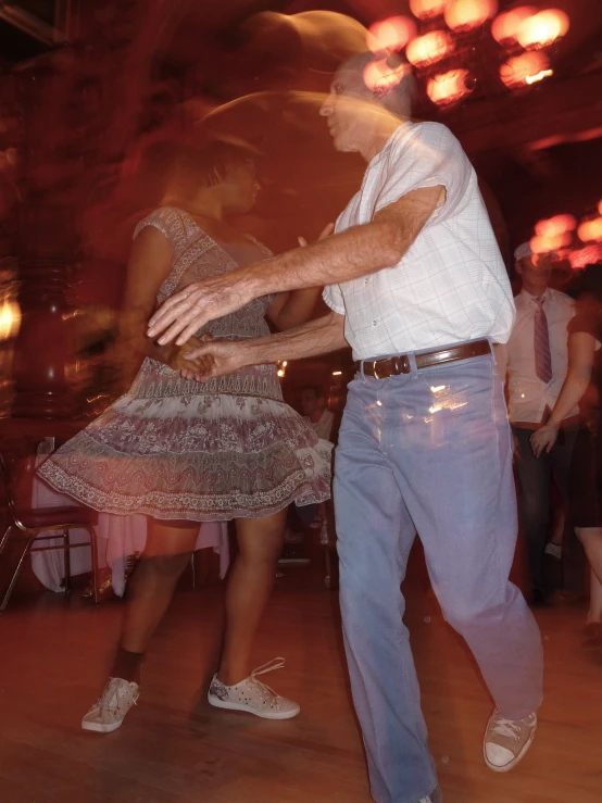 two people dance at a party as others walk by