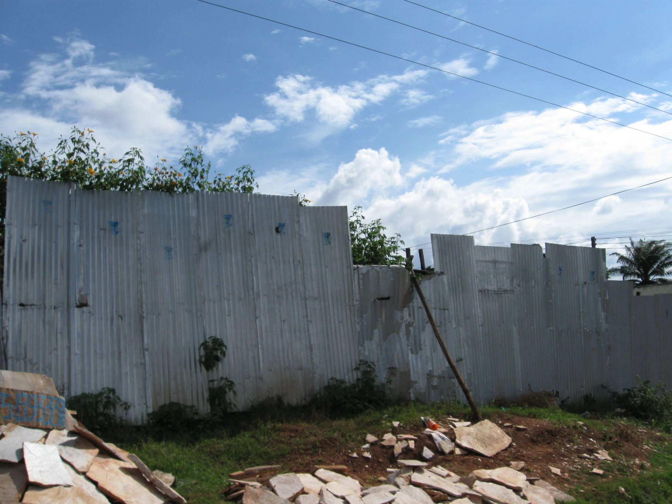 a white fence stands next to several rocks and grass