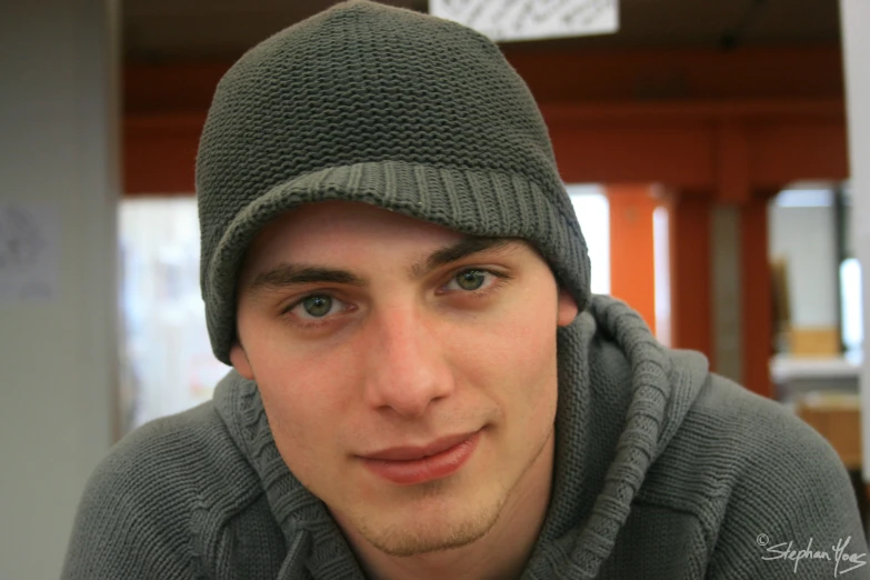 a man wearing a gray sweater with a hat on his head