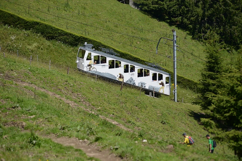 a train on a train track near grassy field and hill