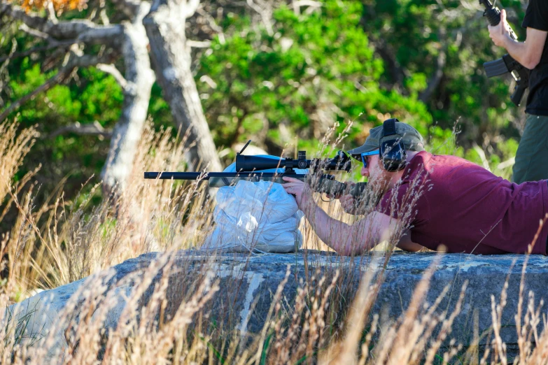 a man aiming a rifle through a field