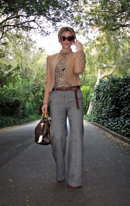 a woman is walking on the road talking on a cell phone