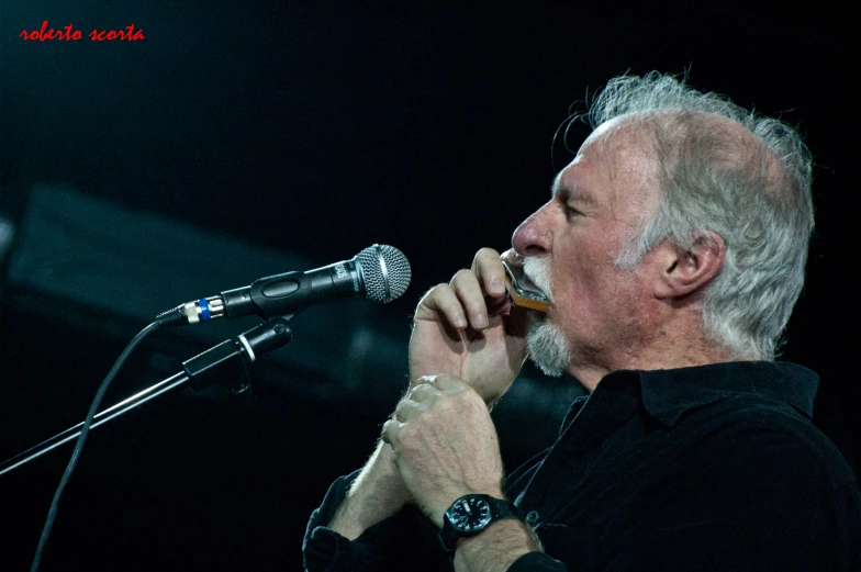 an older man holding up a microphone to his mouth