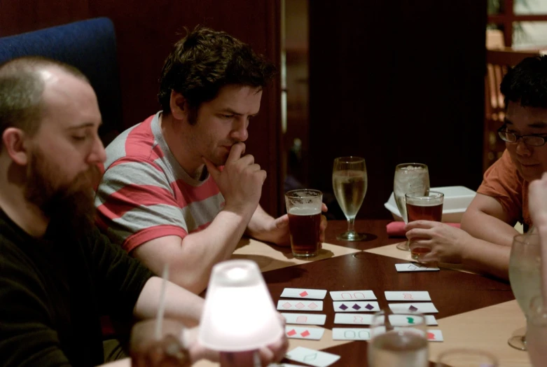 men playing cards on a table with beer glasses