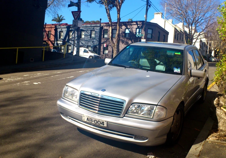 silver mercedes benz parked in street with buildings behind