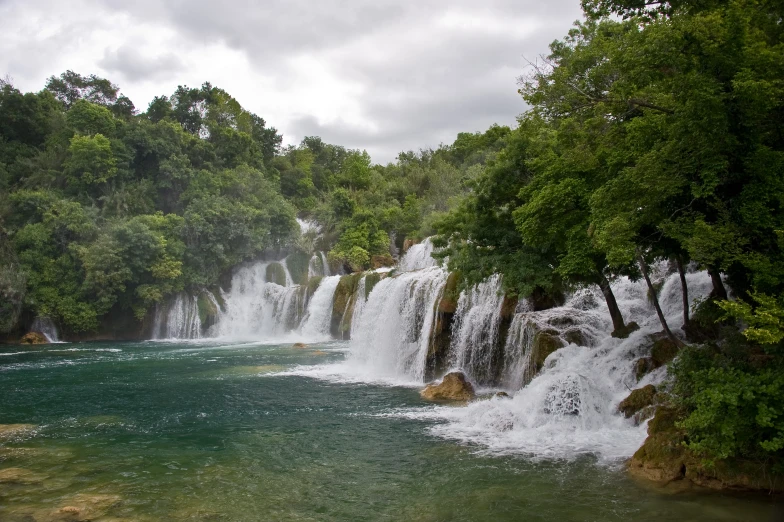 a large waterfall running down the side of a lush green forest