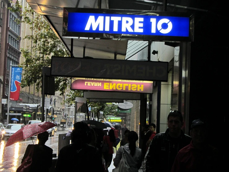 people are standing in the rain under the blue sign
