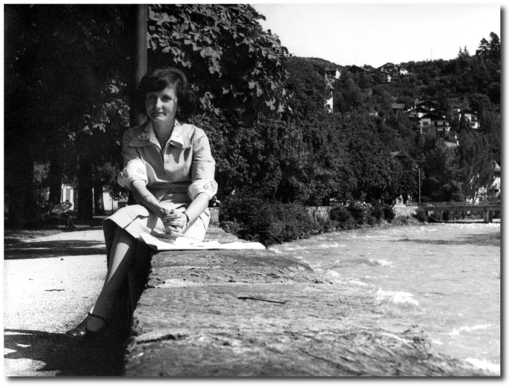 a woman sitting on a park bench near water