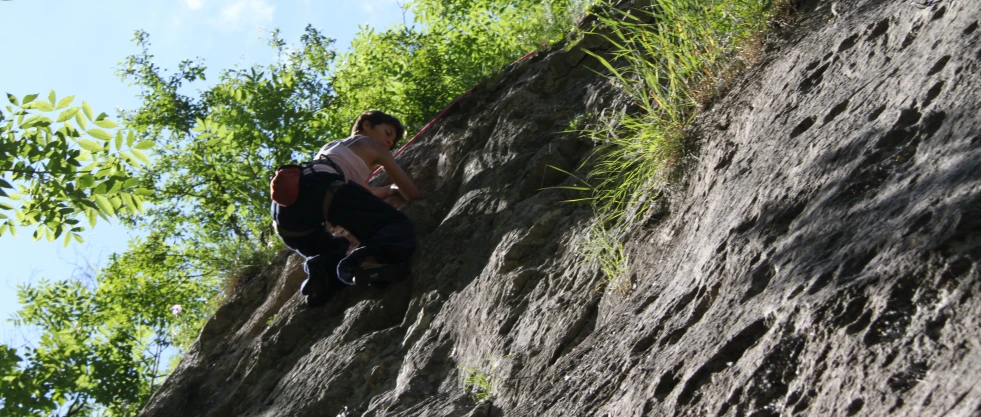 the young man is sitting on the ledge of a cliff