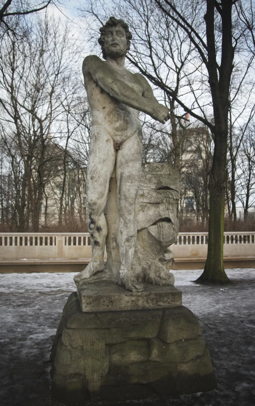 a statue sits in the middle of a park in winter