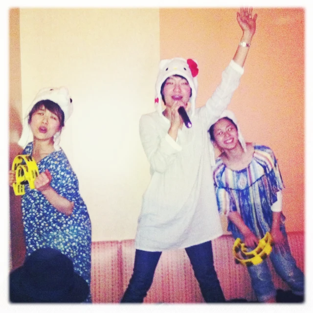 three women in animal hats standing with one holding a banana