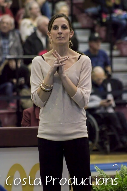 a woman with hands clasped in front of an audience