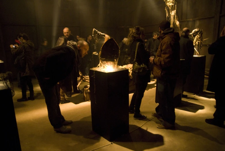 people stand around with their hands on top of an object in the dark