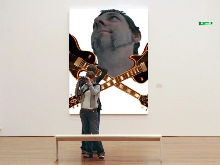 a man is looking at a huge guitar on the wall