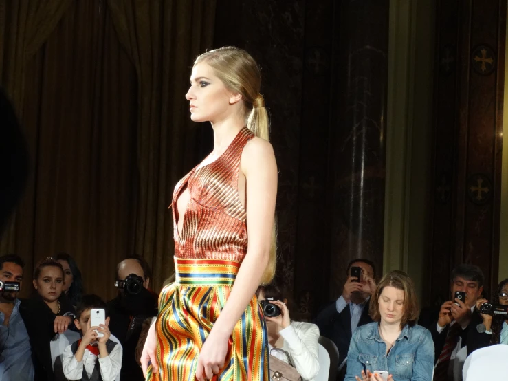 a model is walking down the catwalk as her picture is taken