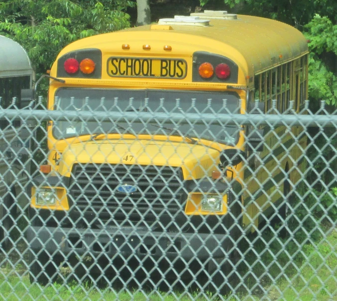 a close up of a school bus behind a chain link fence