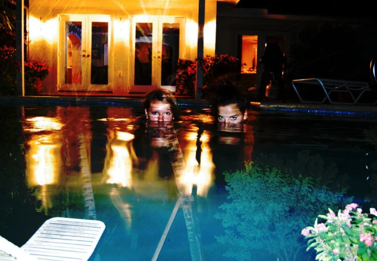 two people floating in an outdoor pool at night