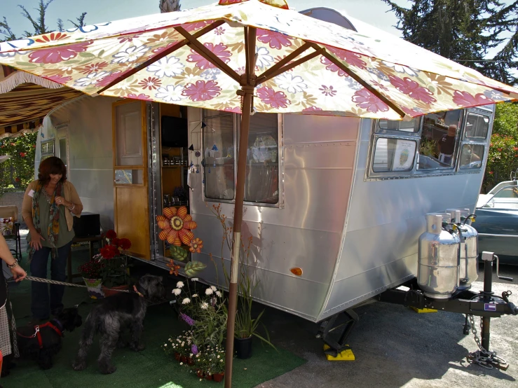 a woman and a dog near a tiny trailer