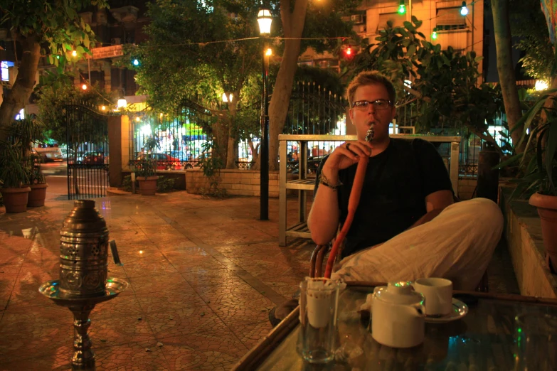 a man is sitting outside with his cane in his mouth